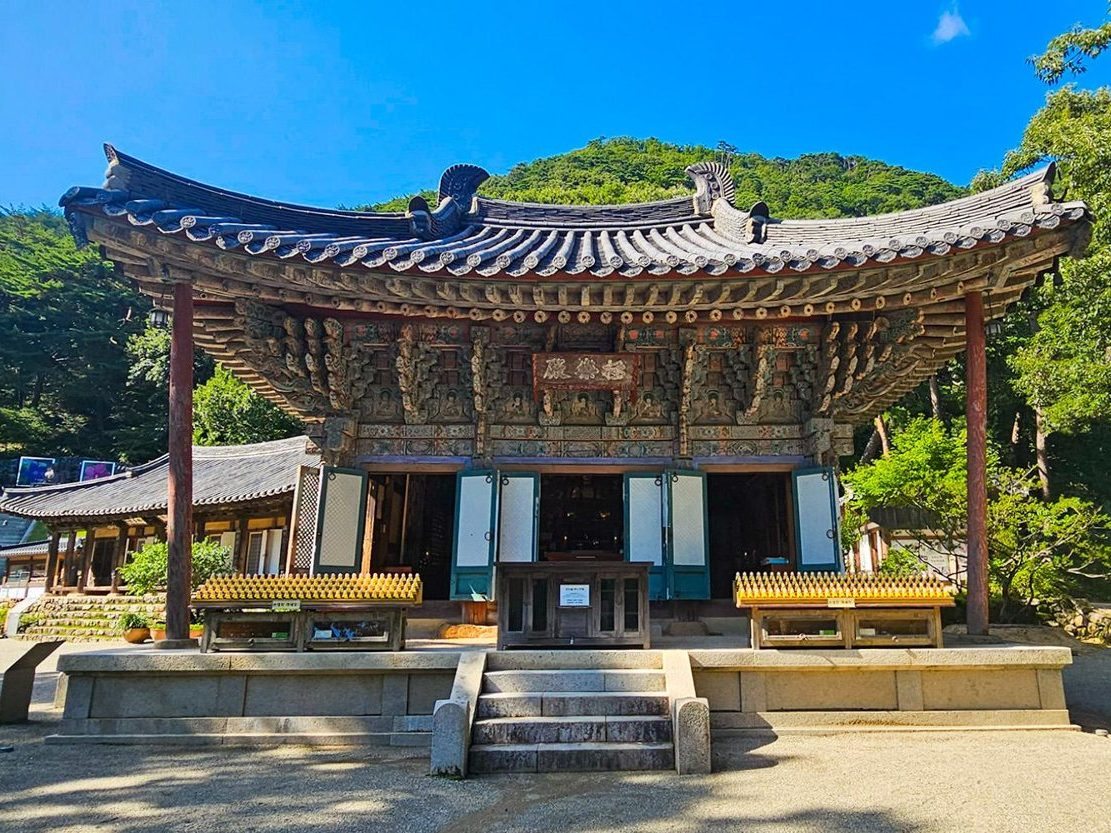 정면에서 본 단청 전각과 돌 기단, 뒤의 초록 산